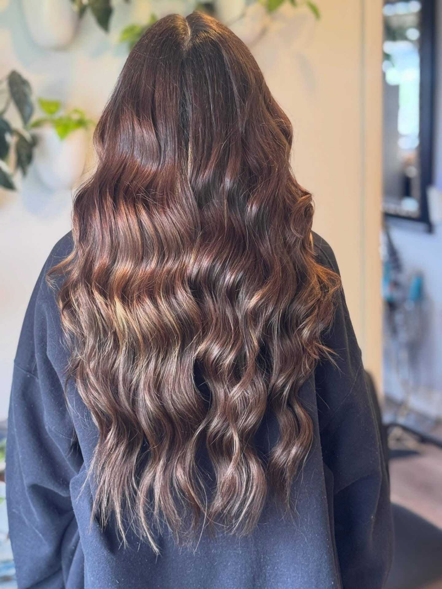 Long, wavy, brunette hair cascading down a person's back, indoors.